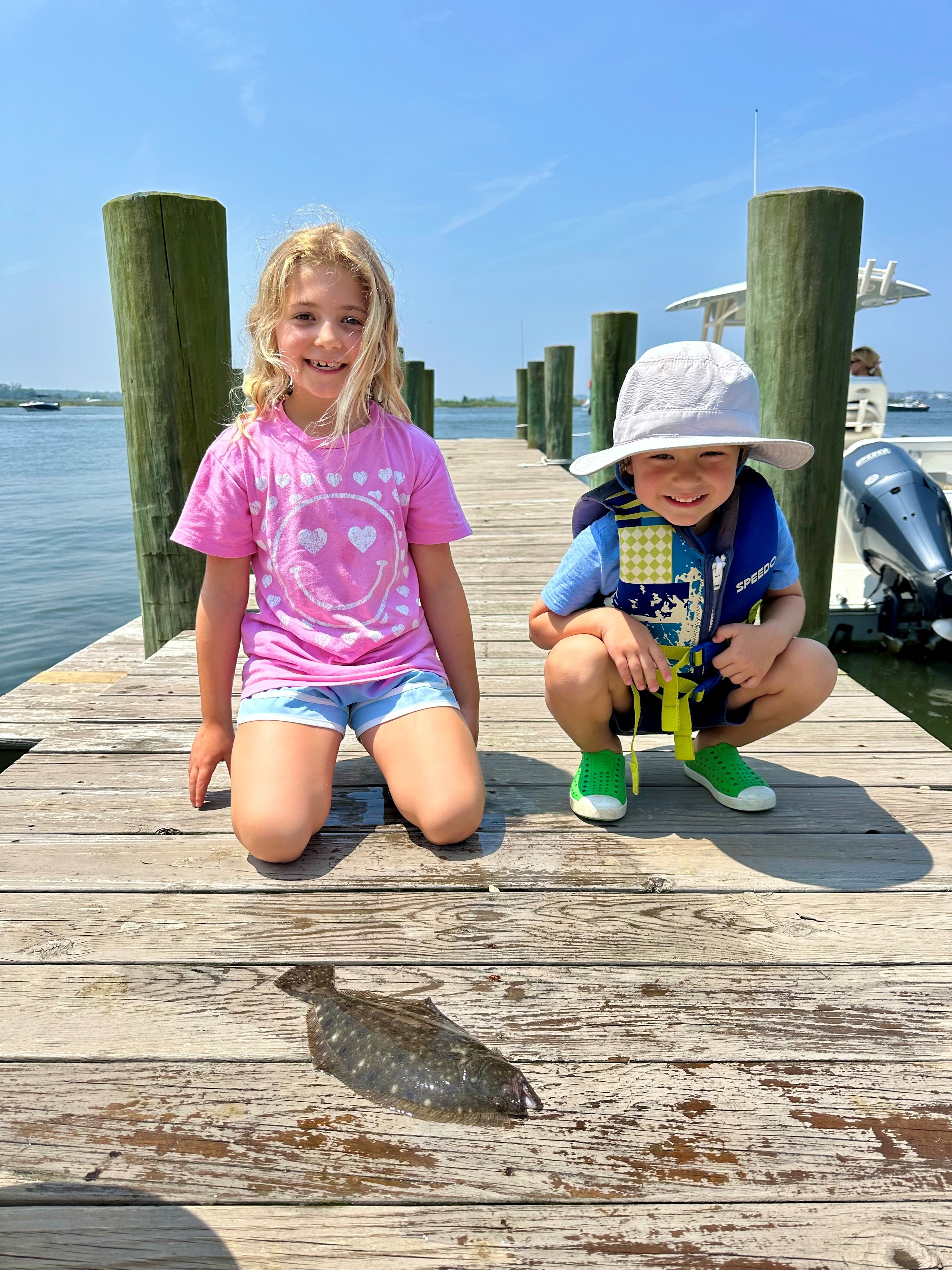 Two kids with a fluke on a dock at the Jersey Shore marina
